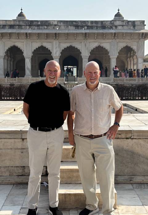       Two travelers pose in front of ornate marble railings inside the Taj Mahal complex
  