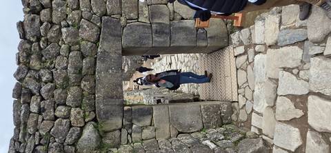       Visitor walks through a stone doorway amid ancient terraces of Machu Picchu
  