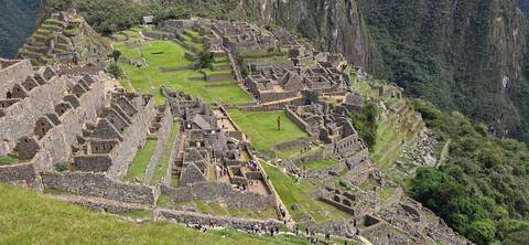       Wide panoramic shot of Machu Picchu citadel nestled on a green ridge
  