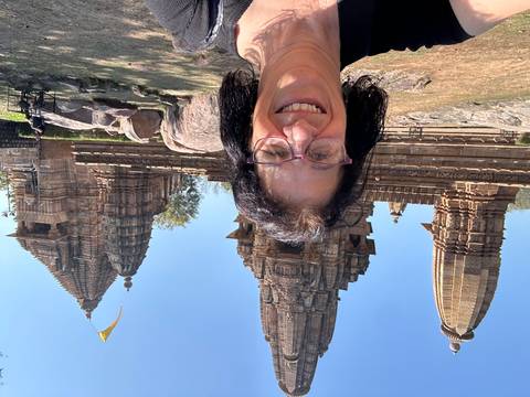       Selfie with intricate Khajuraho temple spires rising in bright daylight
  