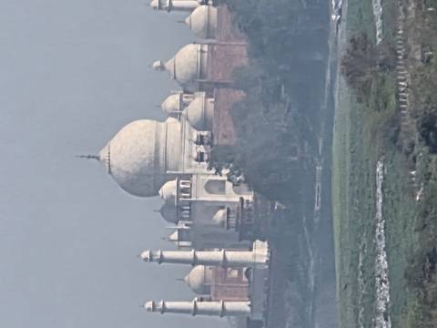       Telephoto hazy view of Taj Mahal dome and minarets under grey sky.
  