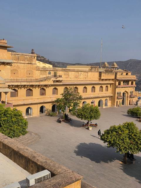       Courtyard and ramparts of Amber Fort in Jaipur viewed from above on sunny afternoon.
  