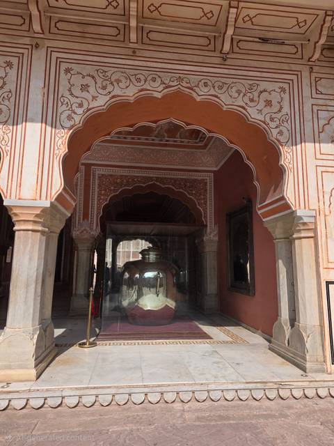       Decorative arched entrance with massive silver urn displayed inside Jaipur City Palace museum.
  