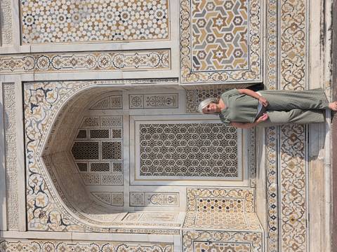       Woman posing beside ornate marble inlay wall at Itimad-ud-Daulah in Agra.
  