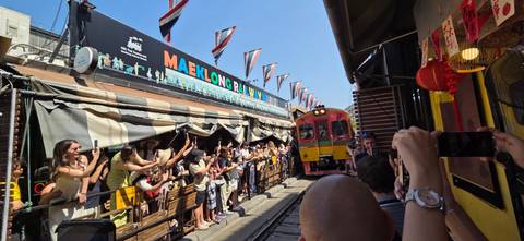       Crowds line the Maeklong Railway Market as a train passes inches from the stalls.
  