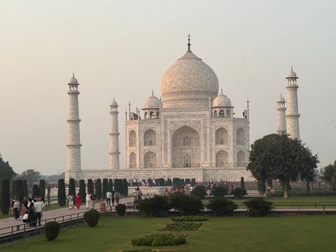       Closer evening view of the marble Taj Mahal framed by gardens and visitors.
  