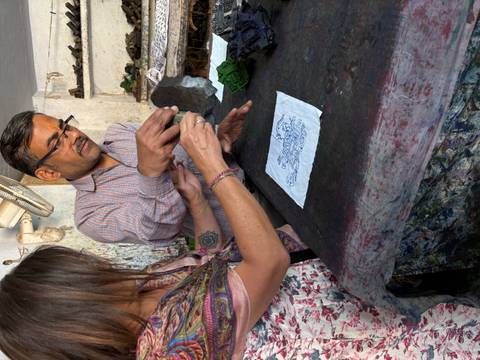       Instructor demonstrates traditional block printing technique to a visitor in a workshop.
  