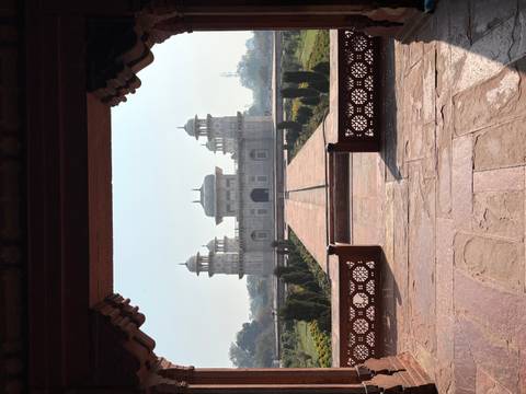       Symmetrical view of the sandstone and marble Itimad-ud-Daulah tomb framed by an arched doorway.
  