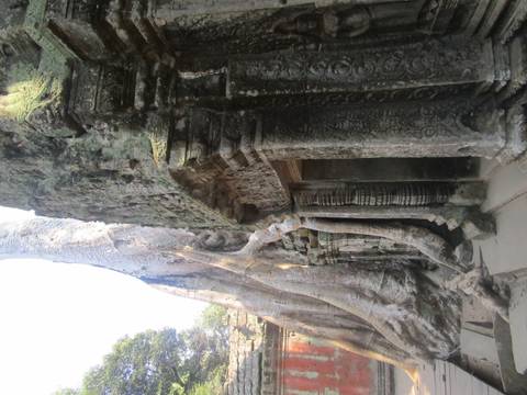       Massive tree roots snake over intricately carved stone doorways of Ta Prohm temple
  