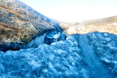       Inside a blue-tinged glacial crevasse with textured ice walls and snow
  