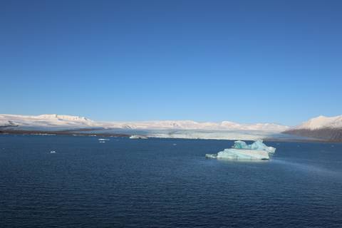       Icebergs floating calmly on the deep blue waters of Jökulsárlón lagoon beneath a clear sky
  