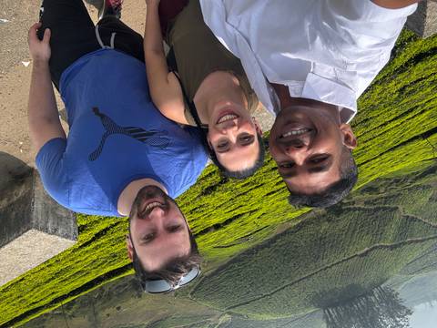       Cheerful selfie of three travellers with vivid green Munnar tea plantations rolling behind them
  