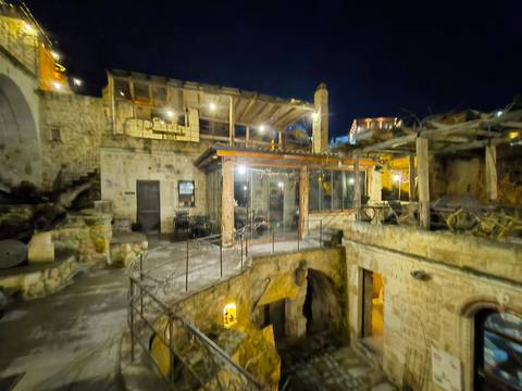       Nighttime view of a cave hotel courtyard with warm lights, appearing soft and out of focus.
  