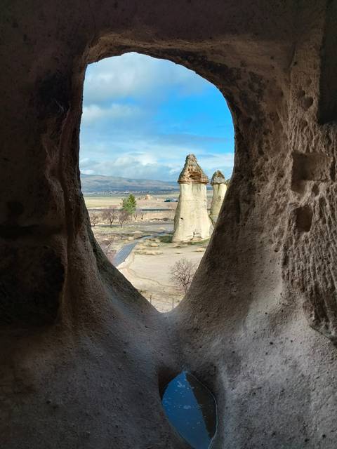       Fairy chimneys viewed through a natural window in a cave dwelling frame the Cappadocian landscape.
  