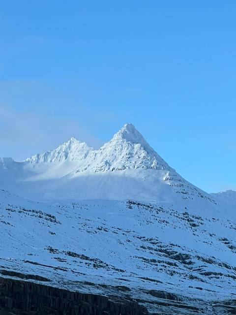       Snow-covered jagged mountain peak under clear blue sky
  