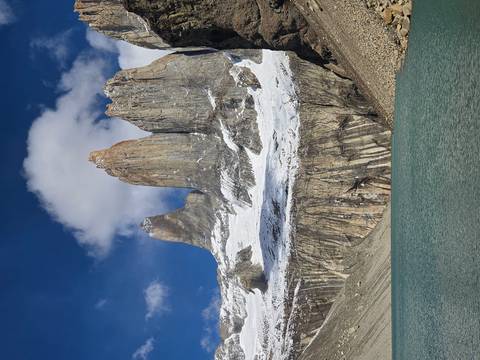       Iconic granite spires of Torres del Paine rise above a turquoise glacial lake under blue skies.
  