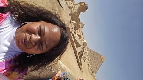       Selfie of a woman at the Great Pyramid and Sphinx under a clear blue sky.
  