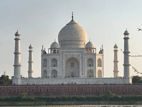       Front view of the Taj Mahal in soft afternoon light with tiny visitors along the plinth.
  