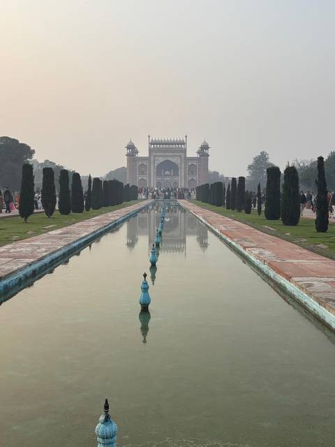       Long reflecting pool leading to the Great Gate of the Taj Mahal complex on a hazy morning.
  