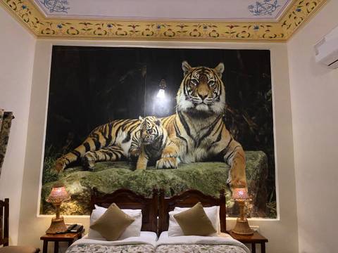       Large photographic mural of a tiger and cub above hotel beds with decorative lamps.
  