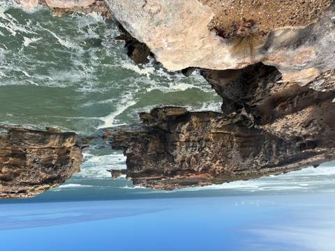       Dramatic rocky cliffs meet swirling green waves along Australia’s rugged southern coastline.
  