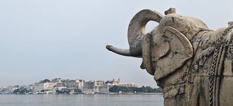       Weathered stone elephant overlooks Udaipur’s City Palace across the lake.
  