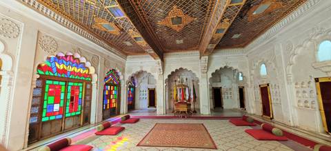      Vibrant room with stained-glass windows and ornate ceilings in an Indian palace.
  