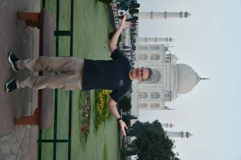       Full-length portrait of a traveler in front of the Taj Mahal and reflecting pool.
  