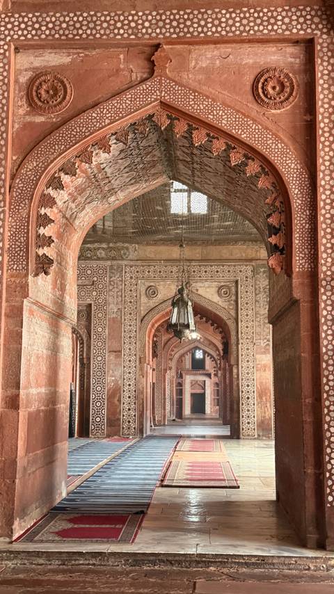      Long sandstone corridor with intricate inlay work and hanging lantern at Fatehpur Sikri.
  