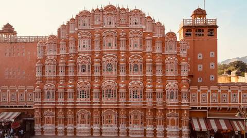       Front façade of Jaipur’s pink-hued Hawa Mahal glowing in warm light.
  