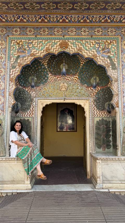       Close-up of the woman seated beside the ornate Peacock Gate’s arch and peacock carvings.
  