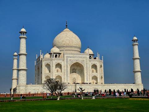       Crystal-clear daytime shot of the Taj Mahal with crowds lining the marble plinth under deep blue sky
  