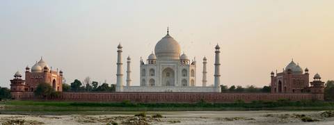       Taj Mahal viewed across Yamuna River at soft sunset light with birds in the sky
  