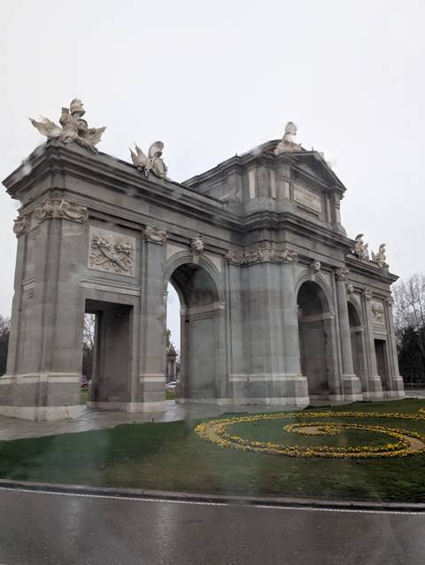       Neoclassical stone triumphal arch standing tall against a grey sky.
  