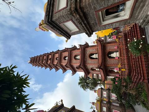       Multi-tiered red pagoda surrounded by lush foliage against a bright morning sky.
  