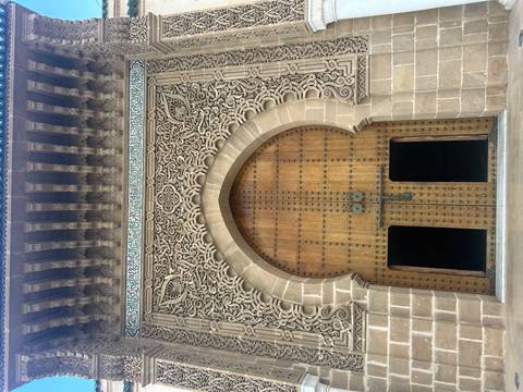       Close view of an elaborately carved wooden and stone Islamic doorway with twin open entrances
  