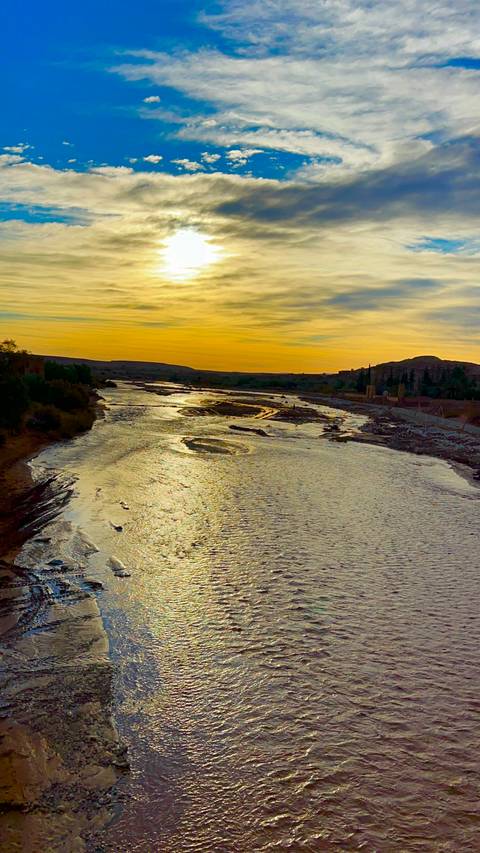       Golden sunset over a reflective desert river winding through arid landscape
  