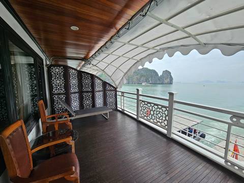       Covered balcony of a cruise boat overlooking the limestone islands of Halong Bay
  