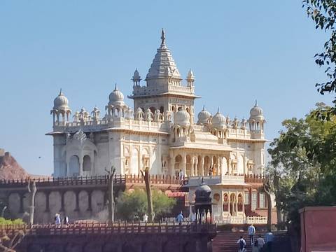       Intricately carved white marble cenotaph set against clear blue sky in Rajasthan
  