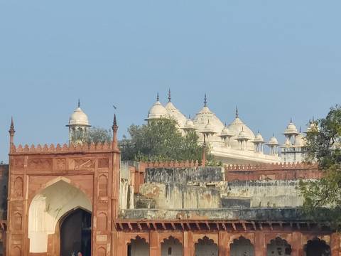       Long low marble pavilions and red sandstone gateway of an Indian palace complex
  