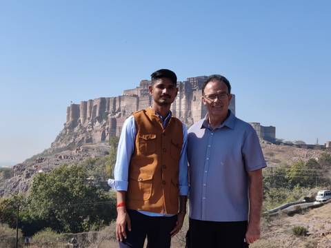       Guide and traveller stand in front of the imposing Mehrangarh Fort in Jodhpur
  