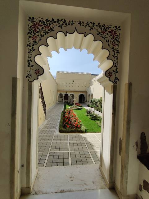       Elegant courtyard garden bordered by cream palace walls and colourful flower beds
  