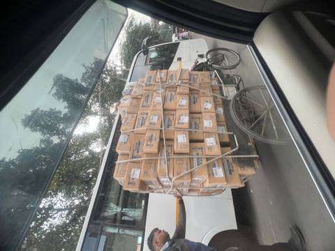       Motion-blurred view from a car of a cycle cart piled with cardboard boxes on a city street.
  