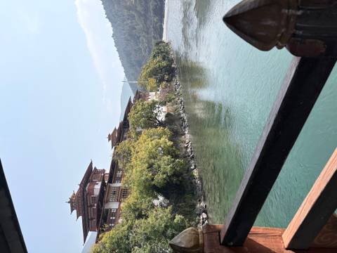       Punakha Dzong stretching along a turquoise river framed by lush green trees.
  