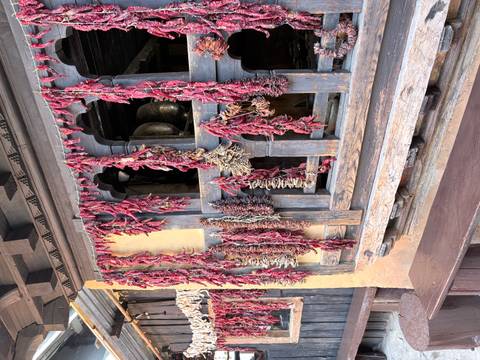       Rows of dried red chilies hanging outside a rustic Bhutanese farmhouse window.
  