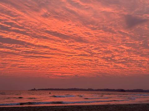       Brilliant crimson sunset sky reflecting over calm ocean horizon in Sri Lanka.
  
