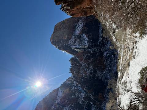       Snow-covered canyon walls rise under a brilliant sun with fresh powder on the valley floor in Zion National Park.
  