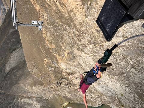       Person diving head-first from a platform on a bungee cord above a rocky canyon.
  