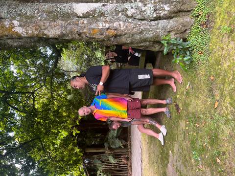      Guide addressing visitors under shady trees in an outdoor cultural setting.
  