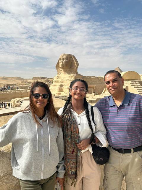       Family poses in front of the Great Sphinx of Giza on a sunny day.
  